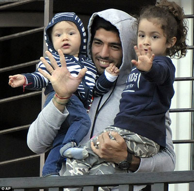 Suarez bế con chào người hâm mộ nhưng anh đang suy sụp sau án phạt kỷ lục Ảnh: AP