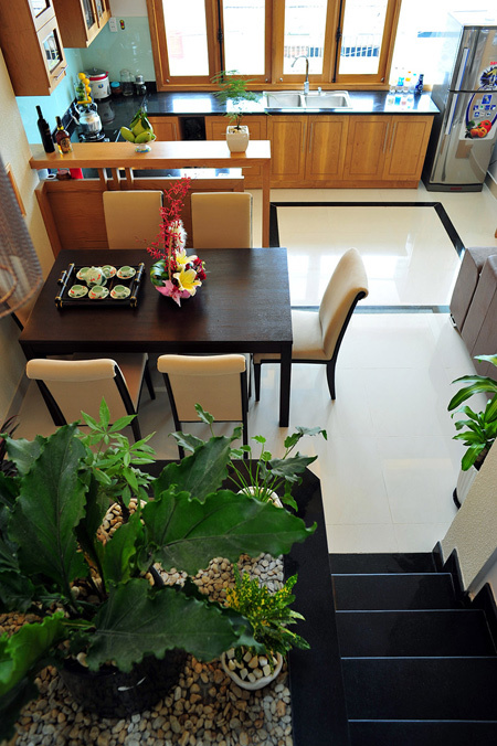 Kh&ocirc;ng như c&aacute;c nh&agrave; phố kh&aacute;c, ở căn nh&agrave; n&agrave;y bếp được đưa ra trước mặt tiền. Diện t&iacute;ch cửa mặt tiền lớn n&ecirc;n đảm bảo sự th&ocirc;ng tho&aacute;ng, dễ chịu khi nấu nướng, đồng thời c&oacute; thể quan s&aacute;t được nh&agrave;. B&agrave;n ăn bố tr&iacute; liền kề với bếp, vừa c&oacute; &aacute;nh s&aacute;ng tự nhi&ecirc;n, vừa gần với tiểu cảnh c&acirc;y xanh.