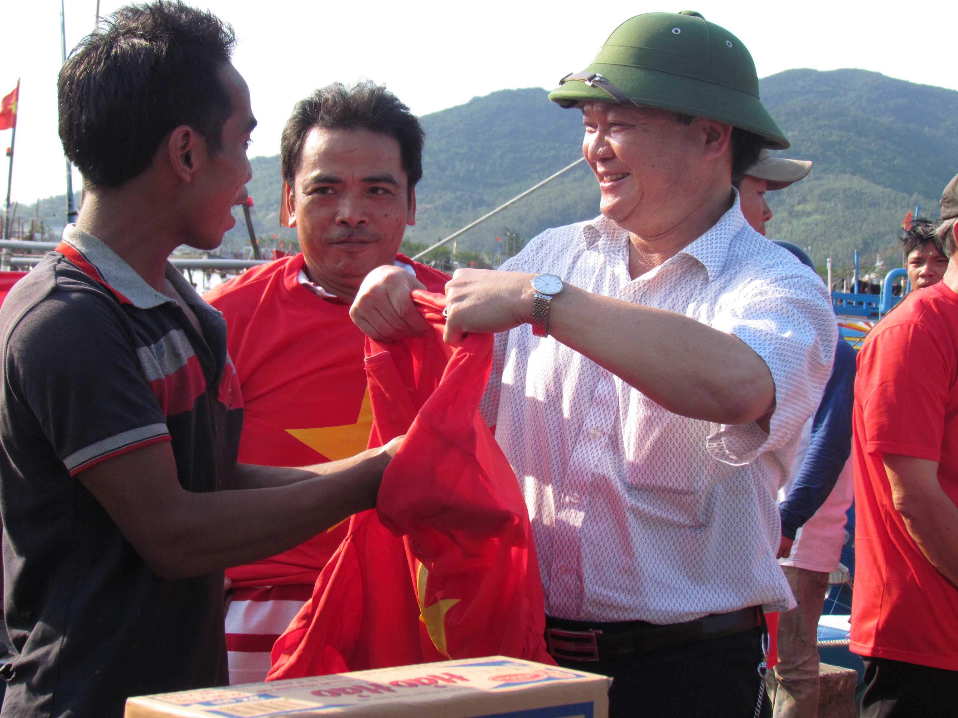 Đại diện Hội Doanh nghiệp quận Hải Ch&acirc;u, TP Đ&agrave; Nẵng trao &aacute;o mang m&agrave;u cờ đỏ sao v&agrave;ng cho ngư d&acirc;n trước khi ra khơi