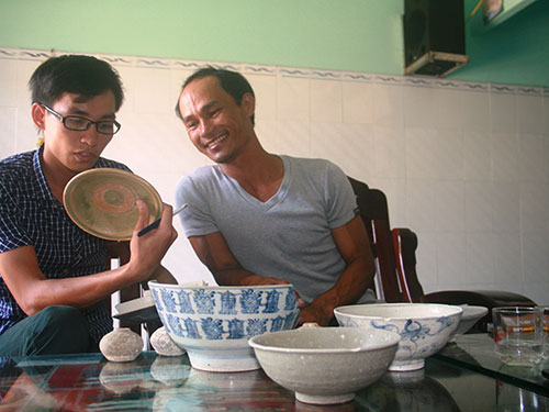 &Ocirc;ng Đinh Tấn T&agrave;u (b&igrave;a phải) giới thiệu c&aacute;c cổ vật m&igrave;nh  vớt được Ảnh: TRẦN THƯỜNG