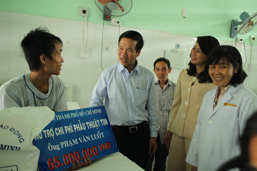 Ông Võ Văn Thưởng trao tiền hỗ trợ cho anh Phạm Văn Luốt (bìa trái)