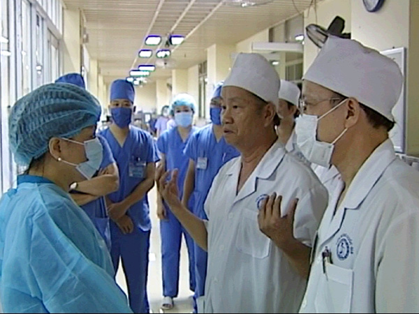 Bộ trưởng Nguyễn Thị Kim Tiến (tr&aacute;i) đang trao đổi với c&aacute;c gi&aacute;o sư, b&aacute;c sĩ Viện Bỏng quốc gia ngay ngo&agrave;i ph&ograve;ng bệnh điều trị 3 chiến sĩ bị thương