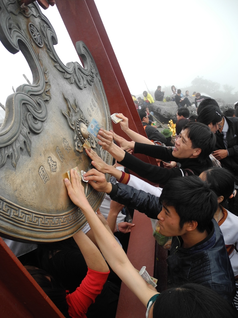 Nhiều du kh&aacute;ch vượt 17 km đi bộ l&ecirc;n Ch&ugrave;a Đồng x&ocirc; đẩy, chen nhau chỉ để cọ tờ tiền v&agrave;o chu&ocirc;ng đồng, ch&ugrave;a đồng lấy may.