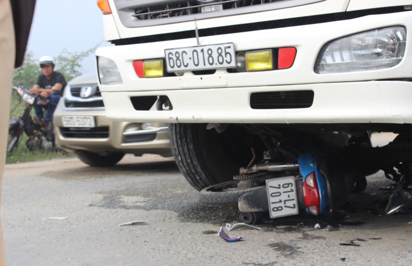 Chiếc xe máy nằm kẹt cứng trong gầm xe tải.