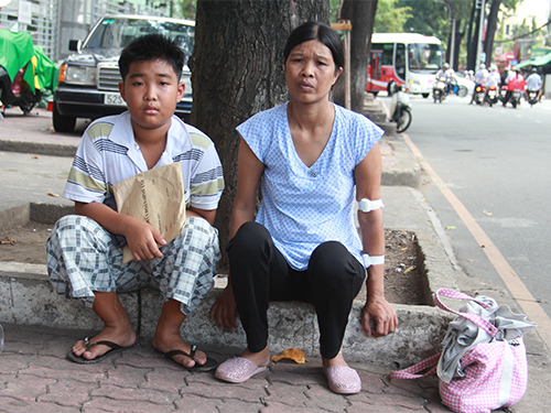 Hai mẹ con chị Đo&agrave;n Thị R&otilde; chờ lấy thuốc ở b&ecirc;n ngo&agrave;i Bệnh viện Nhi Đồng 2