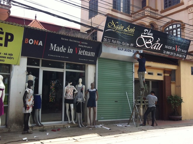 Các cửa hàng đua nhau trưng biển “Made in Việt Nam” trên dải đường dẫn vào trung tâm chợ Ninh Hiệp. Ảnh: Diệp Sa.