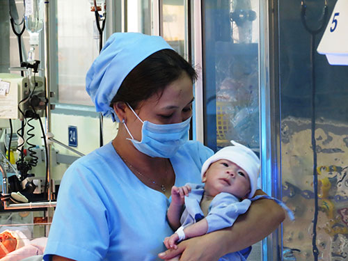 Bé Nguyễn Quốc Huy trong vòng tay của một điều dưỡng viên Bệnh viện Nhi Đồng 1