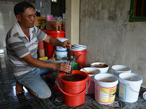 Ông Huỳnh Thanh Hải đang chiết mắm còng vào hũ