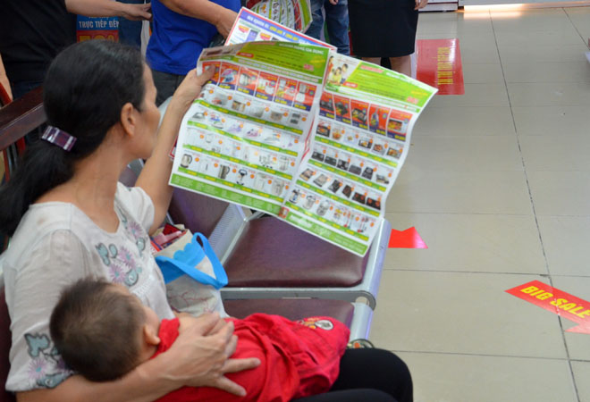 Một phụ nữ &ocirc;m con đến trung t&acirc;m để mua h&agrave;ng giảm gi&aacute;