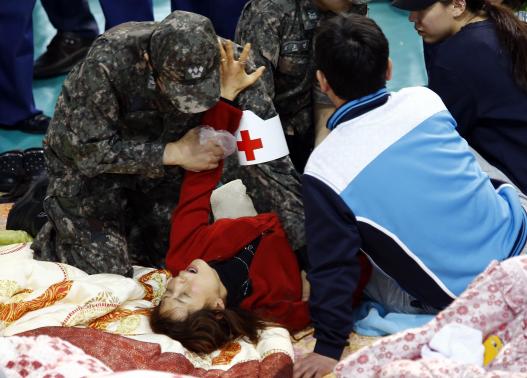 South Korean medics help a collapsed family member of a missing passenger who was on South Korean ferry Sewol which sank in the sea off Jindo, as she cries while waiting for news from a rescue team, at a gym in Jindo April 18, 2014. REUTERS-Kim Kyung-Hoon