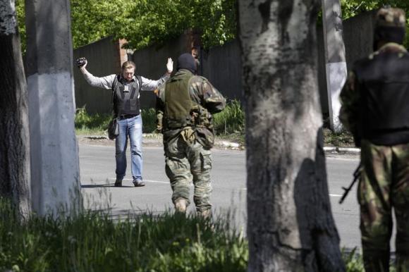 Pro-Russian armed separatists check a journalist at gunpoint in Donetsk May 6, 2014. REUTERS/Konstantin Chernichkin