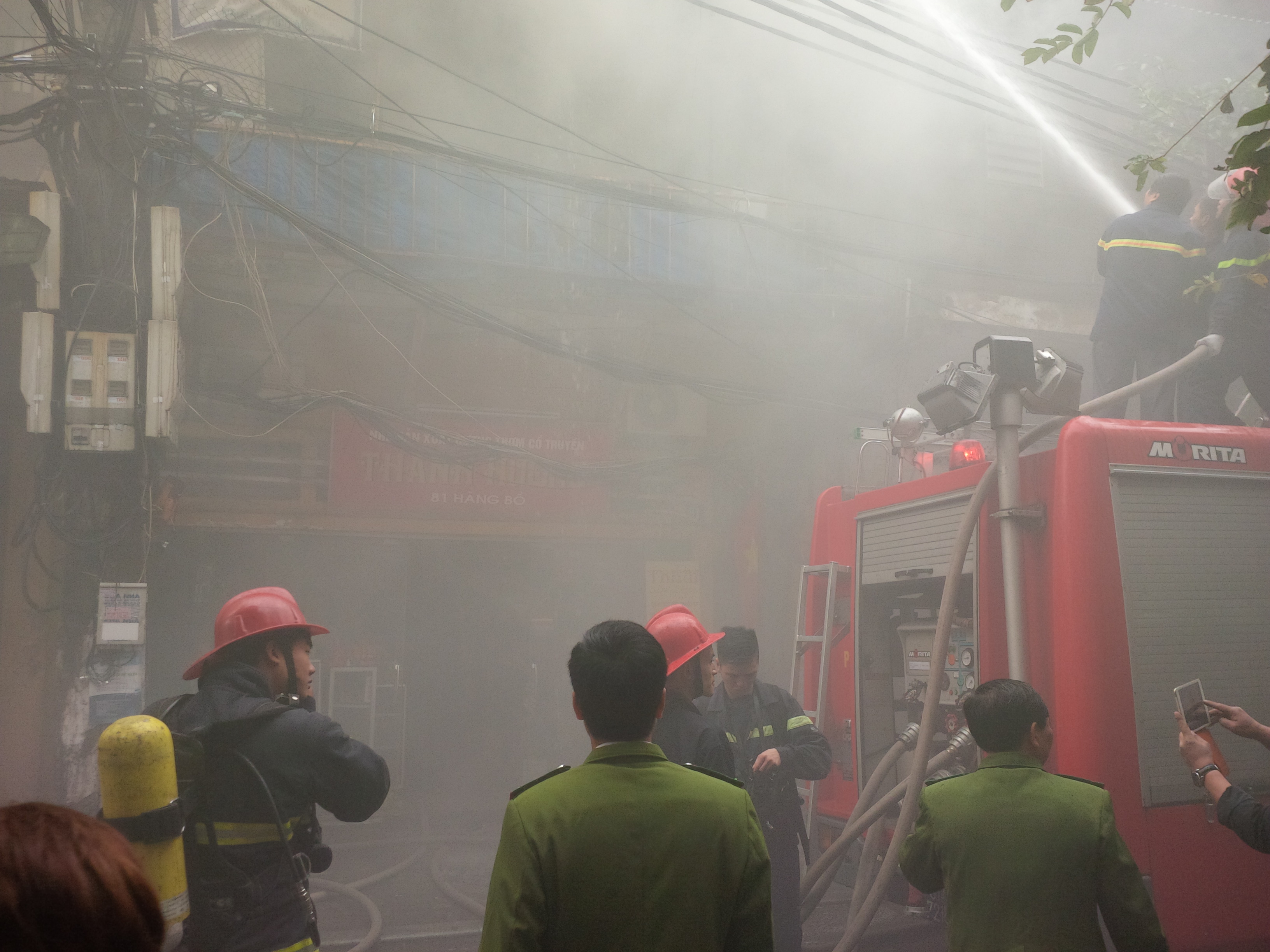 Phun nước trực tiếp v&agrave;o ngọn lửa trong khi kh&oacute;i đen vẫn tu&ocirc;n ra m&ugrave; mịt