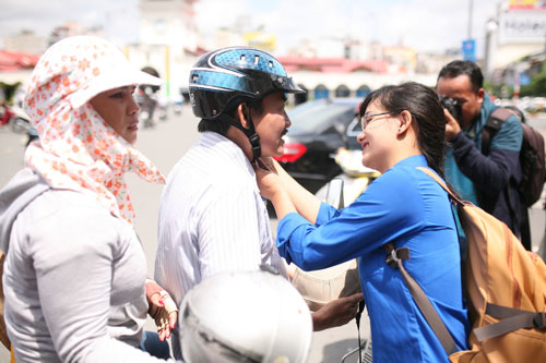 Thanh niên tình nguyện đang cài mũ bảo hiểm đạt chuẩn cho người dân.