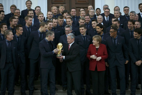 Đội tuyển Đức tại lễ t&ocirc;n vinh ở Phủ Tổng thống (đội ph&oacute; Bastian Schweinsteiger nhận c&uacute;p v&agrave;ng FIFA từ tổng thống , b&ecirc;n cạnh l&agrave; Thủ tướng Angela Merkel)