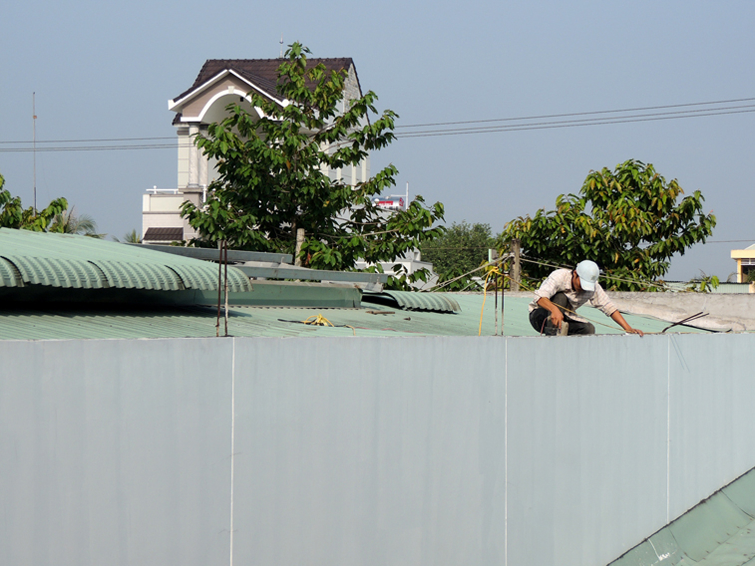 C&ocirc;ng nh&acirc;n leo l&ecirc;n n&oacute;c nh&agrave; kho để th&aacute;o dỡ m&aacute;i t&ocirc;n. Ảnh: D.M.Phương