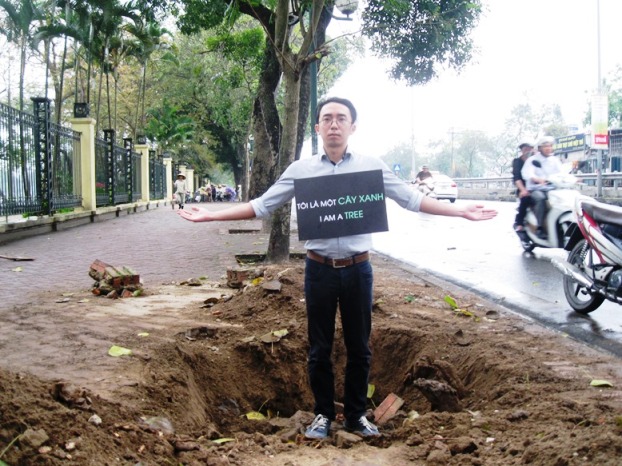 Anh Nguy&ecirc;̃n Anh Tu&acirc;́n với t&acirc;́m bảng giữa trời mưa k&ecirc;u gọi người d&acirc;n chung tay bảo v&ecirc;̣ c&acirc;y xanh trong thành ph&ocirc;́