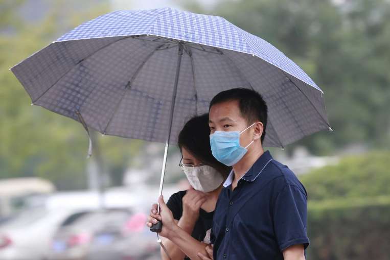 Một cặp đôi che dù đi dưới mưa ở TP Thiên Tân ngày 18-8. Ảnh: Reuters