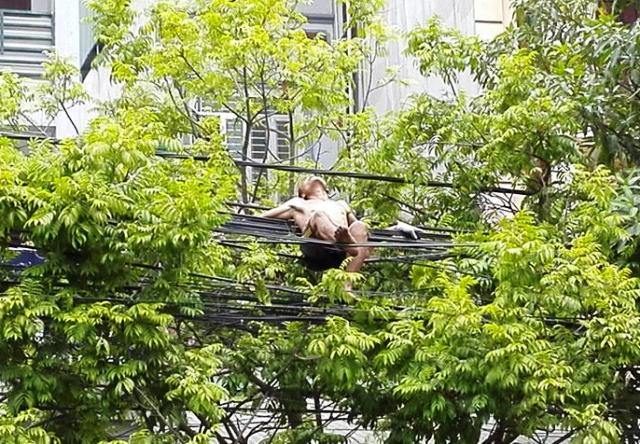 Nam thanh ni&ecirc;n cởi trần nằm vất vưởng tr&ecirc;n đường d&acirc;y điện