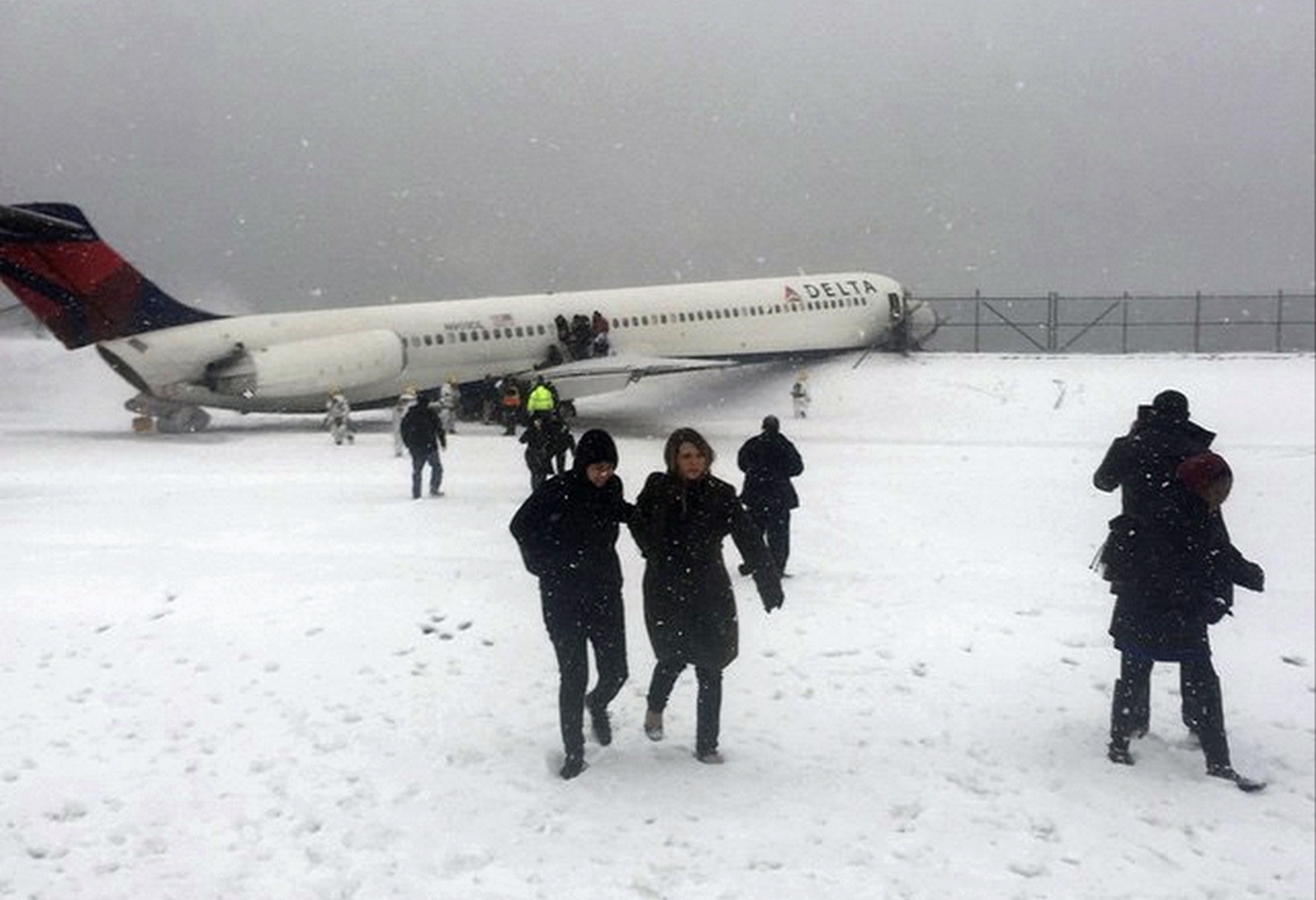 CLICK IMAGE for slideshow: Passengers walk from a Delta jet which skidded off the runway at Laguardia airport in a photo provided by New York Giants N...