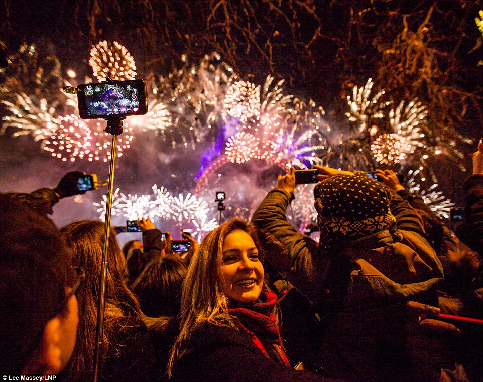 Selfie time: Revellers use their mobile phones to capture the stunning fireworks bonanza. A woman even turns her back on the display momentously to take a selfie