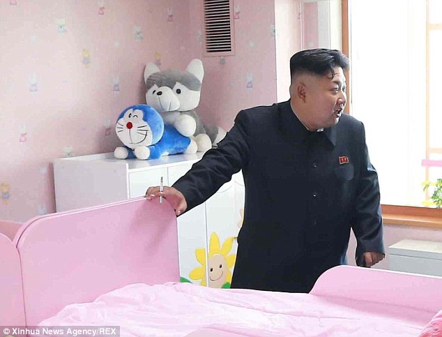 Photobomb: Kim was oblivious to the pair of cuddly toys placed in a compromising position on a wardrobe behind him as he visited an orphanage in Pyongyang in October last year