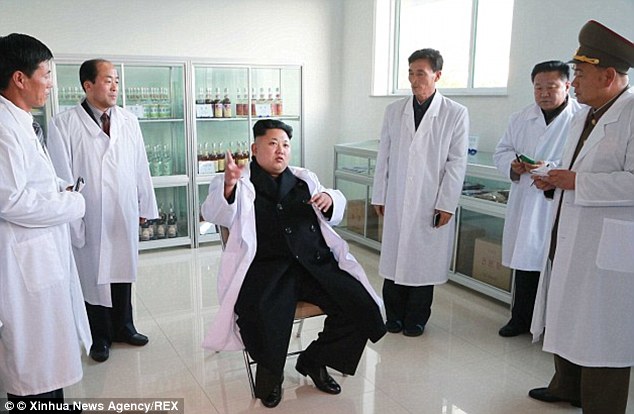 Offering advice: Kim sits in the middle of officials at a food factory last year while offering management tips
