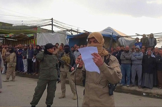 Accusation: An Islamic State militant with a yellow scarf covering his face is seen using a microphone and PA system to read out the charge of 'fornication' -or sex outside marriage - against the couple