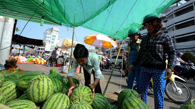 Quầy h&agrave;ng dưa hấu của chị Nguyễn Thị Nhị tr&ecirc;n đường Phan Đăng Lưu quảng c&aacute;o gi&aacute; b&aacute;n 12.000 đồng/kg nhưng kh&aacute;ch trả 10.000 đồng/kg chị cũng b&aacute;n -  Ảnh: Thanh T&ugrave;ng