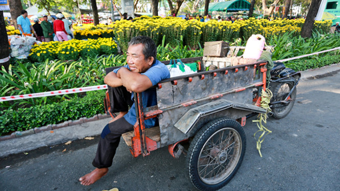 Hoa quả tết kh&ocirc;ng b&aacute;n được k&eacute;o theo nghề chở hoa quả thu&ecirc; cũng ế ẩm. Trong ảnh: &ocirc;ng Nguyễn Văn Ch&acirc;u (ở Q.4, TP.HCM) chờ kh&aacute;ch thu&ecirc; chở hoa quả tết tr&ecirc;n đường Trần Hưng Đạo - Ảnh: Tiến Th&agrave;nh