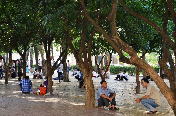Mặc thời ti&ecirc;́t n&oacute;ng bức, các phụ huynh ng&ocirc;̀i la li&ecirc;̣t ở ngoài đợi con em m&igrave;nh