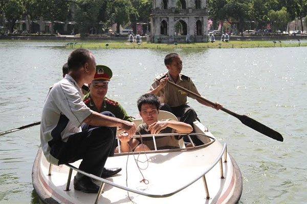 Cảnh s&aacute;t trật tự Hồ Gươm c&ugrave;ng lực lượng bảo vệ phải d&ugrave;ng thuyền ra Th&aacute;p R&ugrave;a để đưa nam thanh ni&ecirc;n n&agrave;y l&ecirc;n bờ