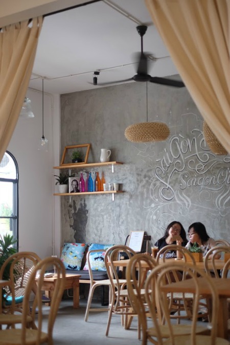Những chiếc ghế bành tre màu vàng óng, quạt trần xoay đen tuyền thân thuộc, kệ sách gỗ xinh xắn đem tới cảm giác thân quen, gần gũi. Điểm ấn tượng của quán là những bức tường viết chữ bay bổng.