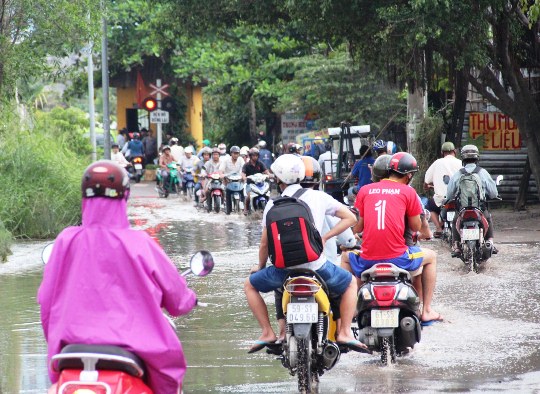Người d&acirc;n kh&oacute; khăn di chuyển qua vũng nước đen tr&ecirc;n đường Linh Đ&ocirc;ng (quận Thủ Đức) để về nh&agrave; sau giờ tan tầm