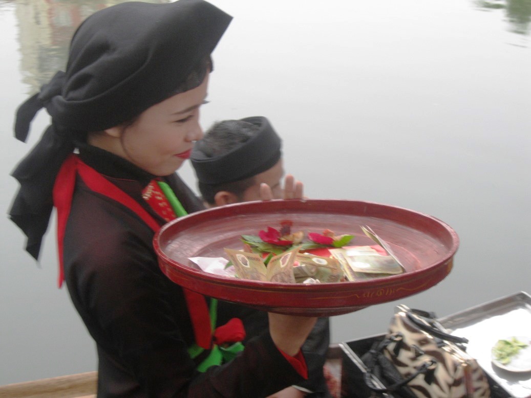 Một liền chị đưa khay trầu nhận tiền sau khi h&aacute;t