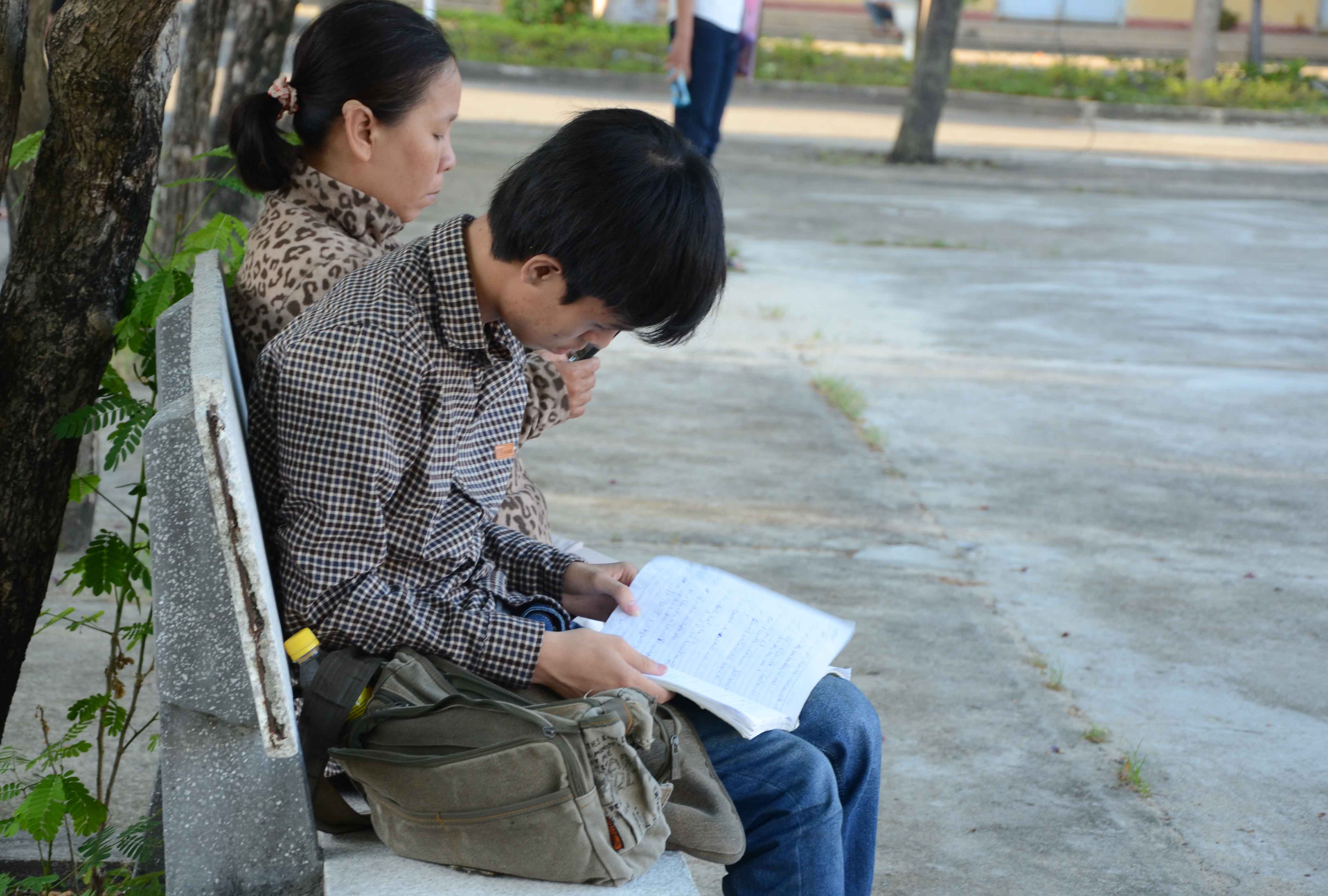 Mẹ ngồi cạnh con đang &ocirc;n b&agrave;i trước giờ thi ngay trong khu&ocirc;n vi&ecirc;n trường