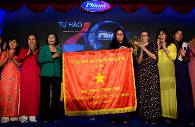 Lãnh đạo Thành ủy (trái) trao cờ truyền thống của UBND TP cho Tổng biên tập Báo Phụ Nữ TP HCM