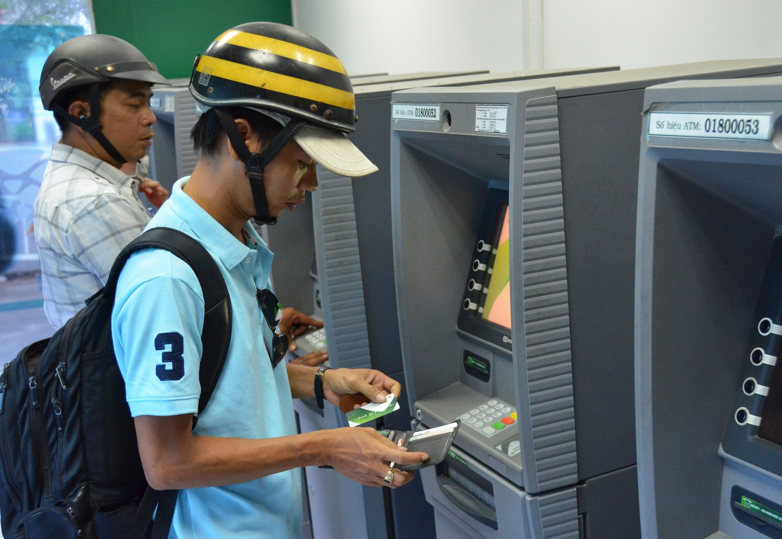 C&ocirc;ng nh&acirc;n r&uacute;t tiền tại c&aacute;c m&aacute;y ATM ở KCX T&acirc;n Thuận, TP HCM (ảnh lớn) v&agrave; một m&aacute;y ATM tr&ecirc;n đường B&agrave; Huyện Thanh Quan (quận 3) kh&ocirc;ng hoạt động trong s&aacute;ng 9-2 (ảnh nhỏ)Ảnh: Tấn Thạnh