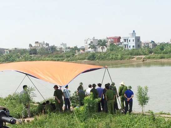 Lực lượng chức năng đang kh&aacute;m nghiệm tử thi sau khi vớt được thi thể nạn nh&acirc;n - Ảnh: CAND