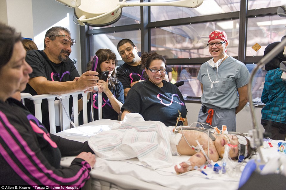 Doctors and family members gather around the other girl as she recovers from surgery. The operation to separate them lasted a total of 26 hours