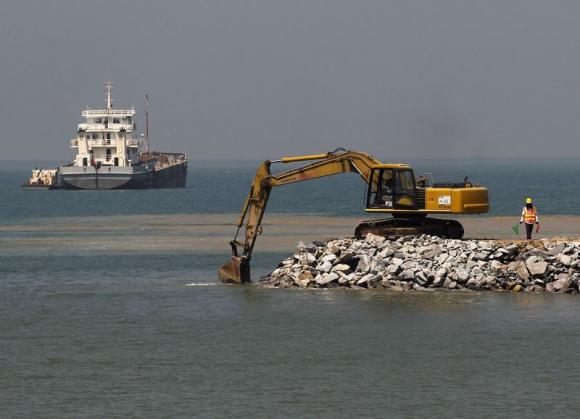 A worker inspects before an excavator is used to reclaim the seafront at a construction site of Chinese investment Colombo Port City in Colombo February 20, 2015. REUTERS/Dinuka Liyanawatte
