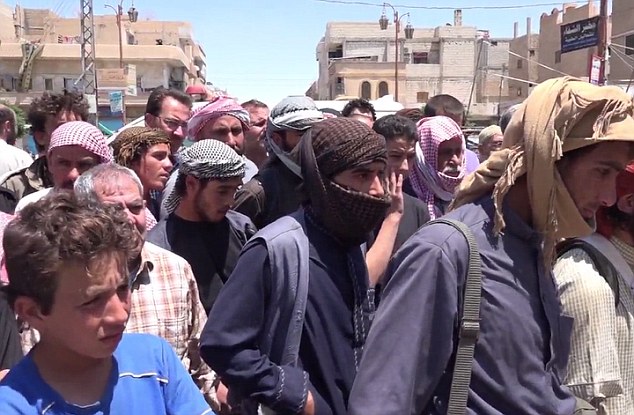 Crowd: Hundreds of men and young boys watch on (pictured) as the men are mutilated in a public square, supposedly in the Syrian city of Homs