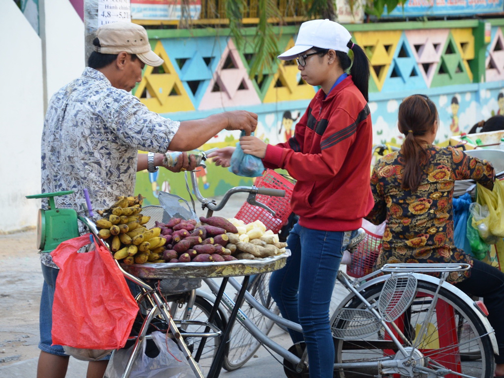 Nữ công nhân mua khoai trước giờ vào ca. ẢNH: NGUYỄN LUÂN