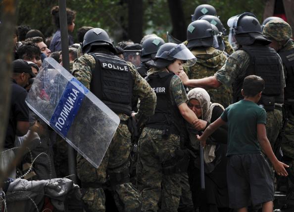 Một người tị nạn ôm hôn tay cảnh sát khi qua được biên giới Macedonia. Ảnh: Reuters
