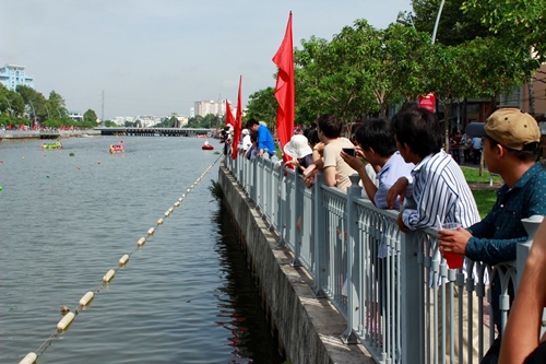 Người d&acirc;n hai bờ k&ecirc;nh theo dõi vào dùng đi&ecirc;̣n thoại ghi lại cảnh đua thuy&ecirc;̀n
