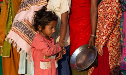 Một đứa bé nép mình cạnh mẹ giữa dòng người xếp hàng nhận lương thực ở Kathmandu - Nepal Ảnh: EPA