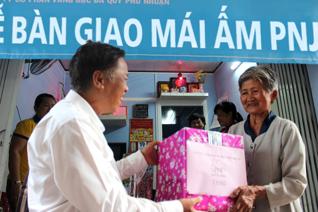 Ông Nguyễn Vũ Phan, Phó Tổng Giám đốc Công ty PNJ trao quà mừng tân gia cho gia đình bà Nguyễn Thị Bé