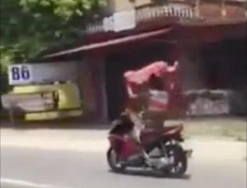 Nam thanh ni&ecirc;n giơ cao 2 tay cầm &aacute;o che nắng, l&aacute;i xe bằng ch&acirc;n - Ảnh cắt từ clip