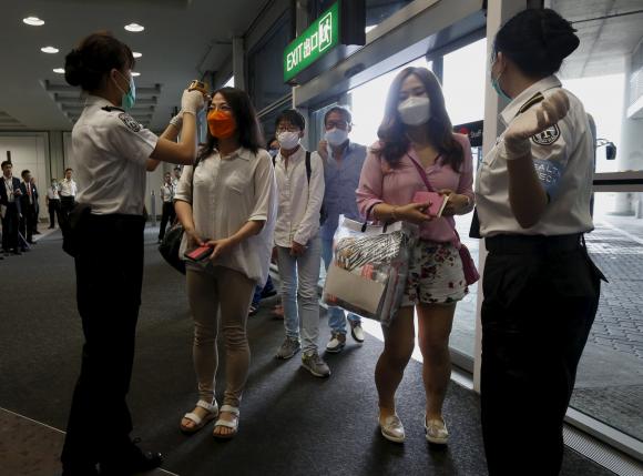 Du kh&aacute;ch H&agrave;n Quốc được kiểm tra th&acirc;n nhiệt tại s&acirc;n bay Hồng K&ocirc;ng. Ảnh: Reuters