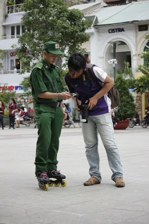 Một chiến sĩ TNXP đang chia sẻ th&ocirc;ng tin về đội TNXP trượt patin một người d&acirc;n tr&ecirc;n phố đi bộ.