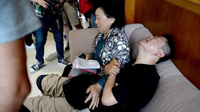 Thân nhân hành khách khóc ngất khi chưa biết tin tức. Ảnh: Reuters